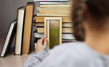 Smart cute girl opening a tiny door in the house of books, beam of lights through the door, studio shot, study and education conceptの写真素材