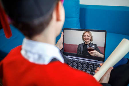 Virtual graduation and convocation ceremony. Excited student wearing graduation gown and cap talking...