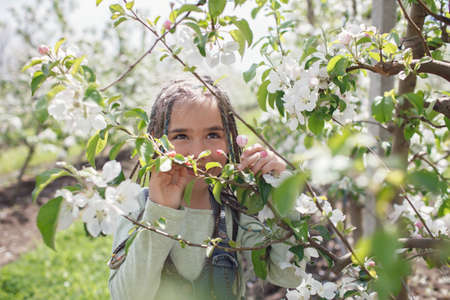 Pretty preteen girl walking in the blooming apple garden in spring, relax and freedom, beauty of...