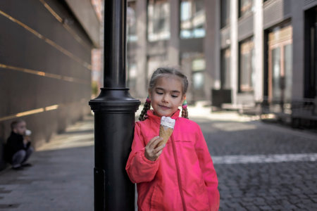 Pretty girl eating ice cream at street over urban background, funny candy girl enjoy sweet dessert and have a fun, street food, outside lifestyleの写真素材