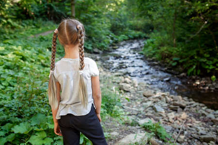 A cute girl walking in the woods, solo tourist hiking to explore nature and discover herself, wellness and slow living concept, summer outdoor activityの写真素材
