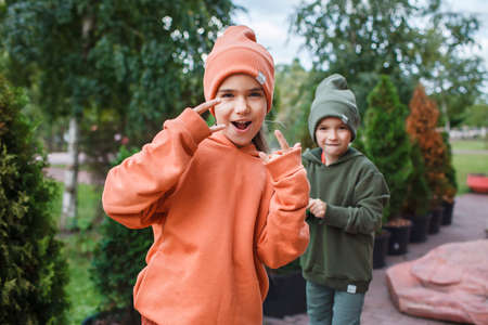 Kids in trendy hats and hoodies having fun in the park, fall vibes, autumn beauty style, child fashion, seasonal fashion. Outdoor active lifestyleの写真素材