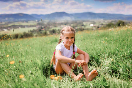 Attractive girl relaxing on the green grass after her morning exercises with dumbbell on the top of the mountains in summer nature, morning exercises, sport and healthy lifestyle, outsideの写真素材