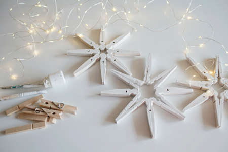 Top view of wooden snowflakes from clothespins painted with white color, recyclable Christmas ornament, New Year DIY decoration, monochrome photography, selective focus on craftの写真素材