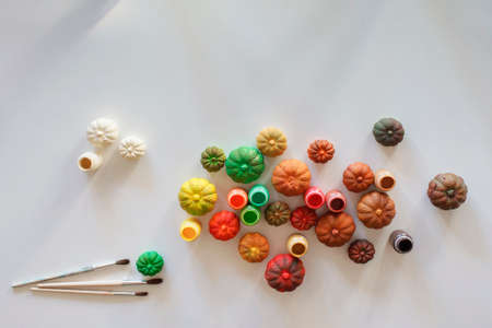 Top view of DIY gypsum pumpkins painted in different bright colors of autumn palette over white background, Halloween and Thanksgiving Day ornament, craft decoration, copy spaceの写真素材