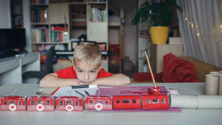 Nice advent calendar like cable cars or train. Little boy dreams near crafted advent calendar with...