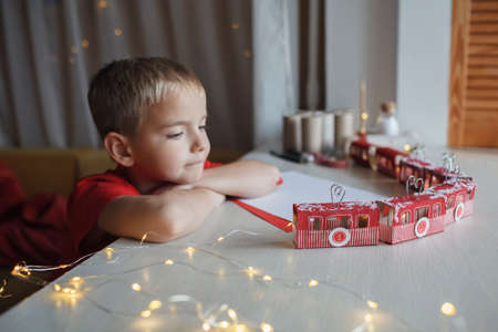 Nice advent calendar like cable cars or train. Little boy dreams near crafted advent calendar with...