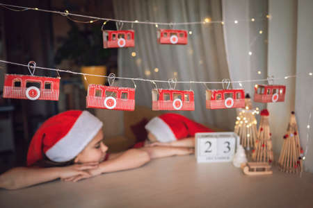 Advent calendar like ski lift on mountain resort. Kids look at funicular cabin with toilette paper roll. Zero waste and reusable Christmas. Magic winter holiday, blurred lights, focus on cable carの写真素材