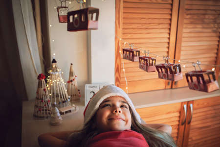 Happy kid dreams by original advent calendar on theme of skis and cable car. Ski resort funicular of rolls from toilette paper. Zero waste and reusable Christmas. Magic winter holiday, focus on girlの写真素材