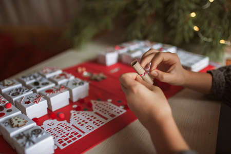 Pretty girl holds an original advent calendar made of jewelry boxes and a binder, New Year craft, diy. Magic of moment, seasonal activity. Christmas miracle. Soft focus, depth of fieldの写真素材