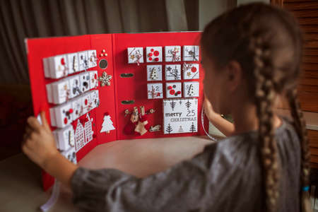 Pretty girl looks at original advent calendar made of jewelry boxes and a binder, New Year craft, diy. Magic of moment, seasonal activity, Christmas miracle. Soft focus, depth of fieldの写真素材