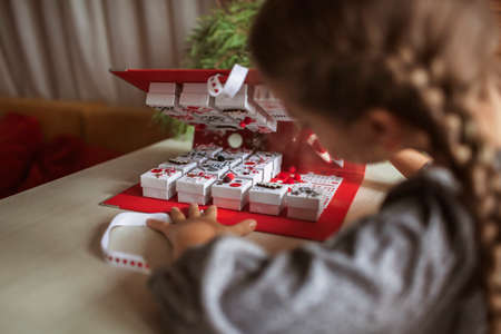 Pretty girl opens an original advent calendar like a book made of jewelry boxes and a binder, New Year craft, diy. Magic of moment, seasonal activity. Christmas miracle. Soft focus, depth of fieldの写真素材