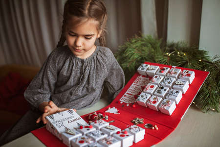 Pretty girl opens an original advent calendar like a book made of jewelry boxes and a binder, New Year craft, diy. Magic of moment, seasonal activity. Christmas miracle. Soft focus, depth of fieldの写真素材
