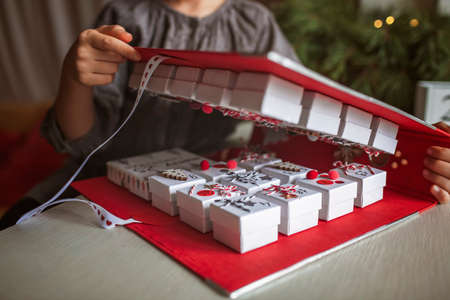 Pretty girl opens an original advent calendar like a book made of jewelry boxes and a binder, New...