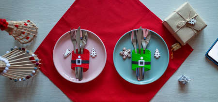 Top view of Christmas tables setting, cutlery and DIY napkin ring holders like Santa clothes made with toilet paper rolls, festive dinner for family with kids. Ecological and sustainable celebrationの写真素材