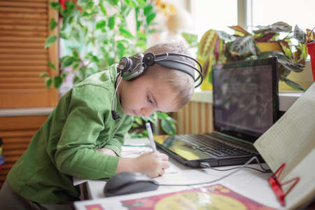 Distant education. Attentive schoolchild studying homework during online lesson at home, social distance during quarantine, self-isolation, communication via internetの写真素材