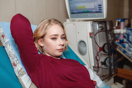Young beautiful girl, during hemodialysis in hospital, dialysis system equipment, habitual routine for chronic patient, lifestyle, medical conceptの写真素材