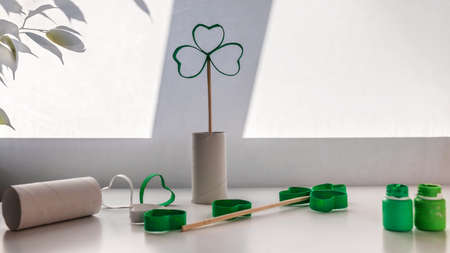 DIY paper clover with toilet roll tube for Saint Patrick Day celebration on the desk before window, zero waste decor for party and celebration, creative idea for kids and adults, banner formatの写真素材