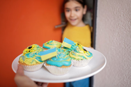 Excited Ukrainian girl for whom the neighbors brought for brunch cupcakes with cream in yellow and...