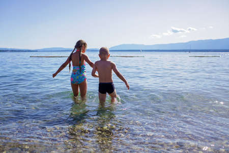 Happy girl and boy going into the blue water, lots of fun and happiness, summer vacations, travel and summertime, lifestyleの写真素材
