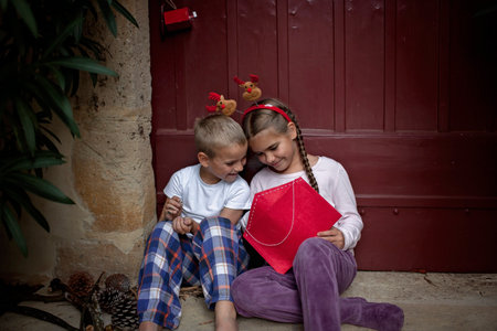 Happy siblings wearing in fun hat write a letter for Santa and dreamily waiting for gifts on Christmas Eve. Winter holidays in different places, Noel traditionの写真素材