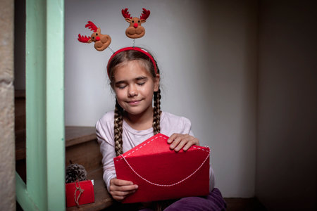 Dreamily girl wearing in fun hat writes a letter for Santa and waiting for gifts on Christmas Eve. Winter holidays in different places, Noel traditionの写真素材