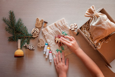 Cute preschool girl doing craft wrapping for festive gifts with wooden stamp printing technique, printing home textile with wooden printing block, zero waste and craft for holiday conceptの写真素材