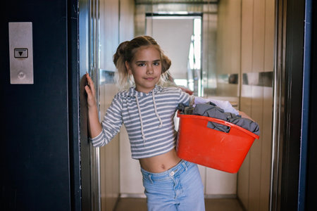 Teenage girl with a laundry basket going to common laundry. Concept of ecology, sustainability, care for environment, as well as saving money and natural resourcesの写真素材