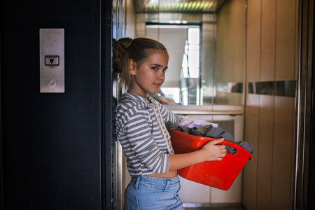 Teenage girl with a laundry basket going to common laundry. Concept of ecology, sustainability, care for environment, as well as saving money and natural resourcesの写真素材