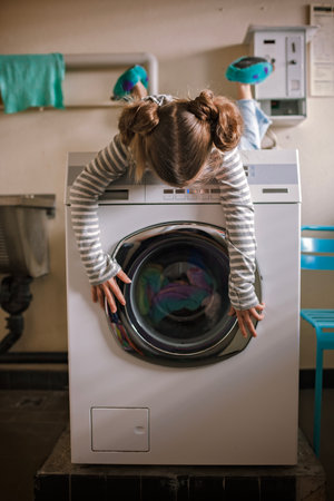 Eco-conscious teenage girl waits in common laundry. Sustainability and responsible living. Efforts to save resources, conserve water, energy, and money. Eco-lifestyle in actionの写真素材