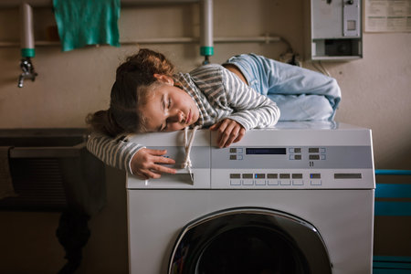 Eco-conscious teenage girl waits in common laundry. Sustainability and responsible living. Efforts to save resources, conserve water, energy, and money. Eco-lifestyle in actionの写真素材