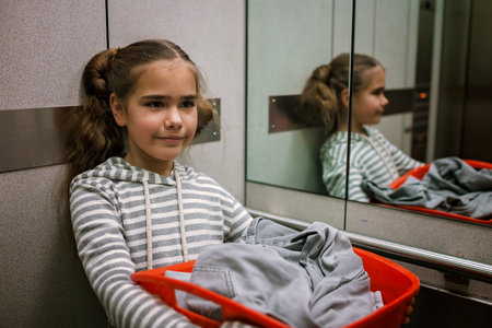 Teenage girl with a laundry basket going to common laundry. Concept of ecology, sustainability, care for environment, as well as saving money and natural resourcesの写真素材