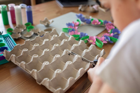 Transformation an ordinary egg carton into a beautiful Easter flower wreath. Kids show the creative and sustainable possibilities of Zero Waste lifestyle. Reduce, reuse, and recycle. DIY with kidsの写真素材