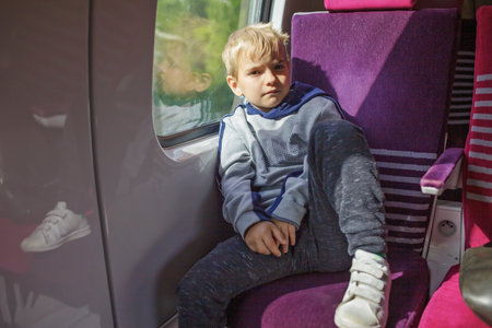Pensive boy on train journey, sunlight accentuating his contemplative mood. A moment away from...