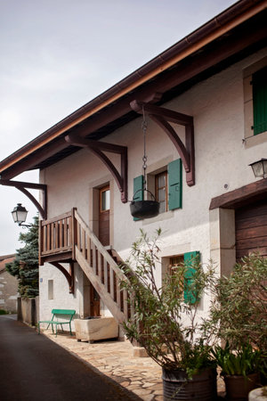 A rustic village house in Europe, complete with wooden beams, green shutters, and a quaint balcony, nestled in a serene street.の写真素材