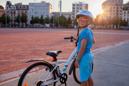 A happy youngster rides a bicycle in a vibrant city setting. The scene highlights the energy and well-being gained from cycling, promoting an active lifestyle with an emphasis on safety.の写真素材
