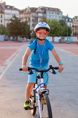 A happy youngster rides a bicycle in a vibrant city setting. The scene highlights the energy and well-being gained from cycling, promoting an active lifestyle with an emphasis on safety.の写真素材