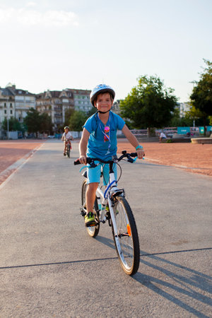 A cheerful child rides a bicycle through the city, wearing a helmet for safetyの写真素材