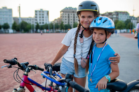 Two confident youngsters enjoy a bike ride in the city, showcasing their friendship and joy. The image highlights health, vitality, and the importance of safety measures like wearing helmets.の写真素材