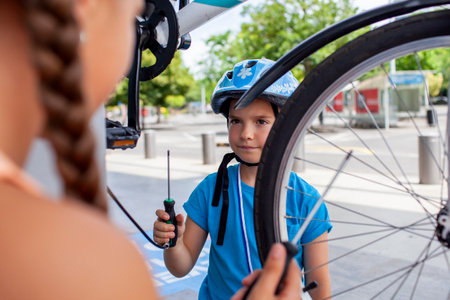 A focused child is engaged in bike repair, showcasing concentration and practical skills. This image highlights hands-on learning, making it ideal for themes of hobbies, family time, and activeの写真素材