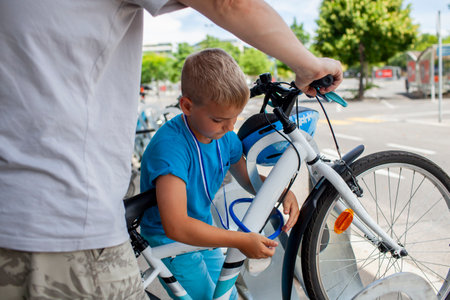 A young child works on a bicycle, fully absorbed in the process of fixing and learning. Perfect for illustrating productive activities, childhood curiosity, and family-oriented hobbies.の写真素材