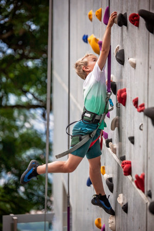This cheerful photo shows a young climber on an indoor wall, full of focus and fun. Ideal for content about energy, strength, child development, and active recreation.の写真素材