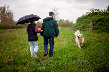 Serene outdoor image capturing family connection in rainy nature. Peaceful slow walk emphasizing presence, emotional safety, and real life bonding.の写真素材