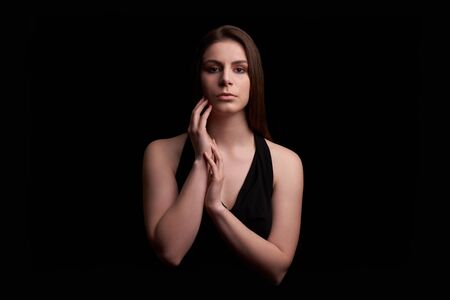 Teenage Girl with hands close to face in black top on black backgroundの写真素材