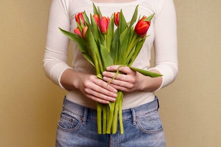 Young Woman in white top and jeans holding bouquet of tulips in her handsの写真素材