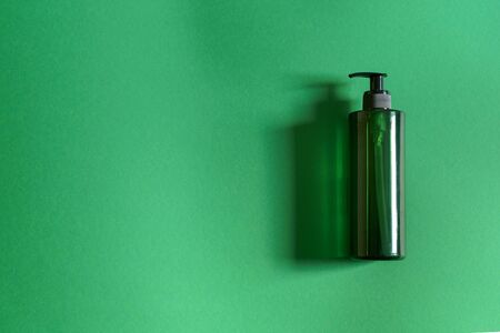 Green plastic cosmetic bottle on green background natural lightの写真素材
