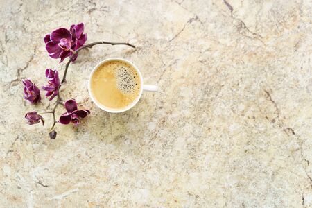 Cup of coffee with orchid flat lay on marble tableの写真素材