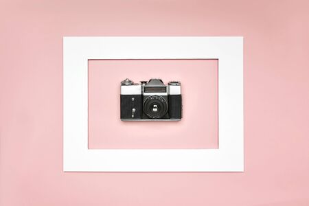 Flat lay old analog camera in the paper frame on pink backgroundの写真素材