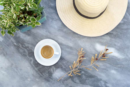straw hat, dry olive tree branch with olives, coffee cup on marble grey tableの写真素材