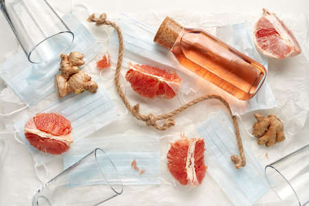 flat lay with medical blue masks, grapefruit, ginger and bottle with drink